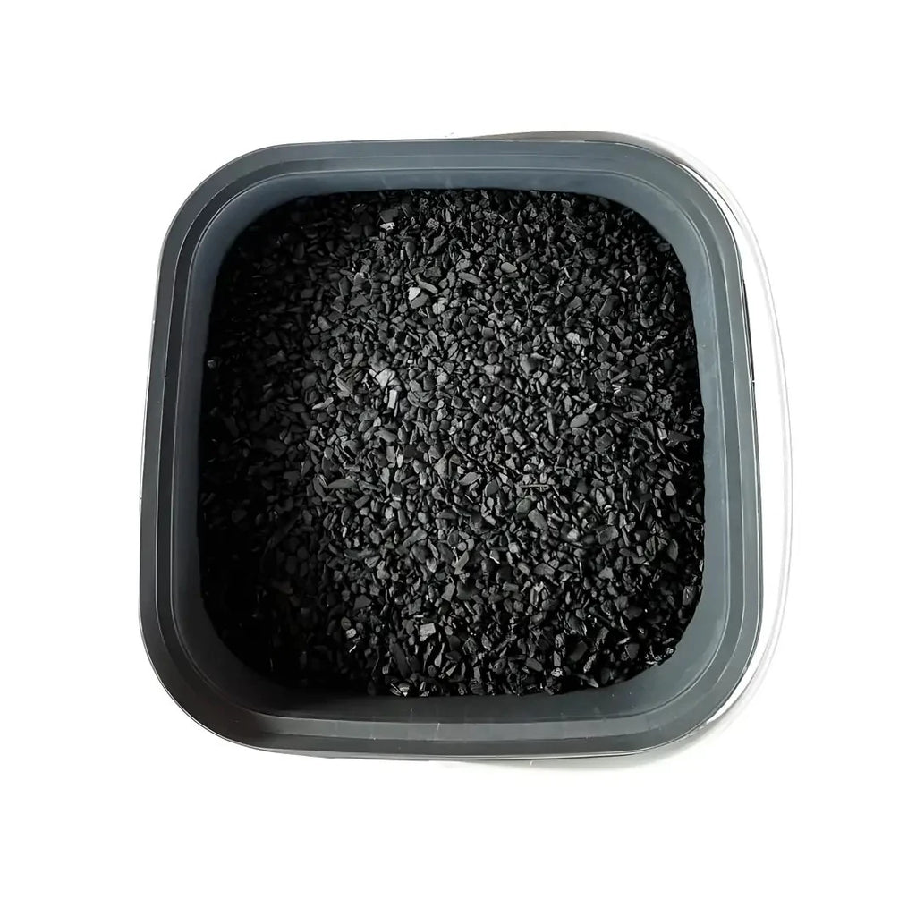 Biochar – gri kare kap içinde eşit yayılmış siyah biochar granülleri, üstten çekim
