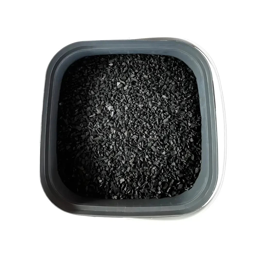 Biochar – gri kare kap içinde eşit yayılmış siyah biochar granülleri, üstten çekim