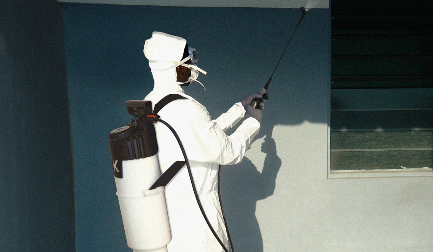 Worker in protective suit spraying disinfectant on indoor wall with sprayer, Trend Ziraat